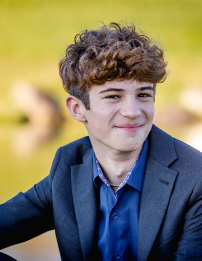 Close-up headshot portrait of a Bar Mitzvah boy smiling confidently during an outdoor photo session at Union League Liberty Hill, captured by PCSI – natural, refined, and personality-driven mitzvah photography