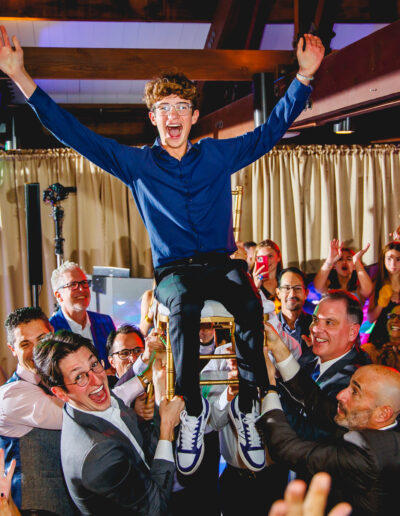 Bar Mitzvah boy lifted on chair during the hora surrounded by cheering guests at Union League Liberty Hill, captured by PCSI – fun, candid, and elegant event photography