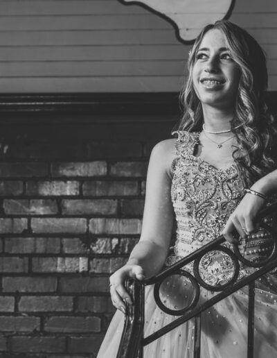 Black-and-white candid portrait of a bat mitzvah girl leaning on a metal stair railing at Beat Street in Huntingdon Valley, PA