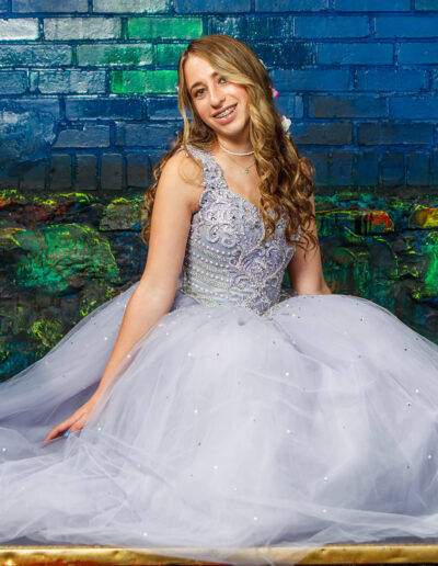 Bat Mitzvah girl in her beaded purple gown posing on the floor surrounded by a colorful background at Beat Street Huntingdon Valley, PA