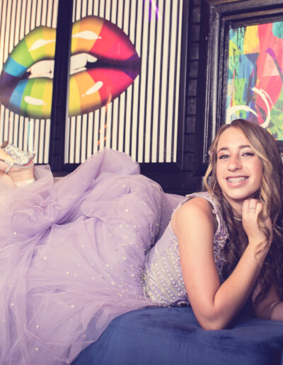 Bat mitzvah girl lounging on a blue velvet sofa in front of colorful pop art deco at Beat Street in Huntingdon Valley, PA