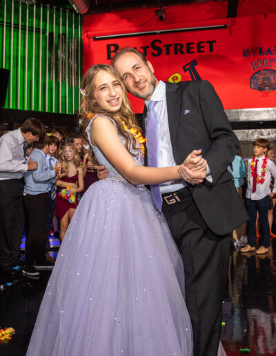Father sporting a purple coordinating tie and daughter in her purple beaded gown sharing a dance at the Bat Mitzvah celebration at Beat Street Huntingdon Valley, Pennsylvania.
