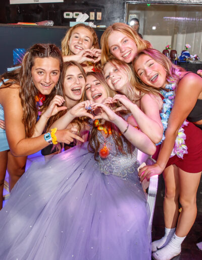 Bat mitzvah girl surrounded by friends making heart shapes with their hands during a tropical-themed celebration at Beat Street Huntingdon Valley, PA