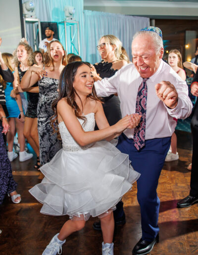 Bat mitzvah girl dancing joyfully with her grandfather and friends in the ballroom at Philmont Country Club in Pennsylvania, photographed by PCSI PHOTO.