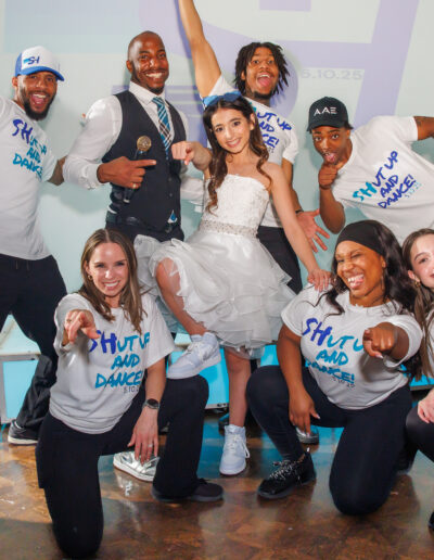 Bat mitzvah girl posing with her high-energy entertainment and dance team wearing dance theme shirts at Philmont Country Club in Philadelphia, photographed by PCSI PHOTO.