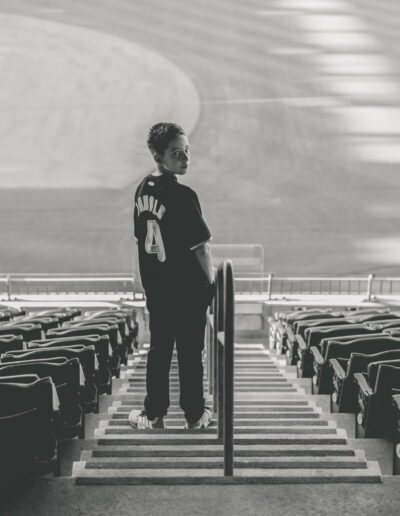 Artistic black and white photo of Bar Mitzvah boy wearing his custom baseball jersey looking reflective inside the stadium at Citizens Bank Park
