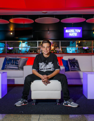 Bar Mitzvah boy smiling and chilling in the lounge area under purple and blue lighting at Citizens Bank Park