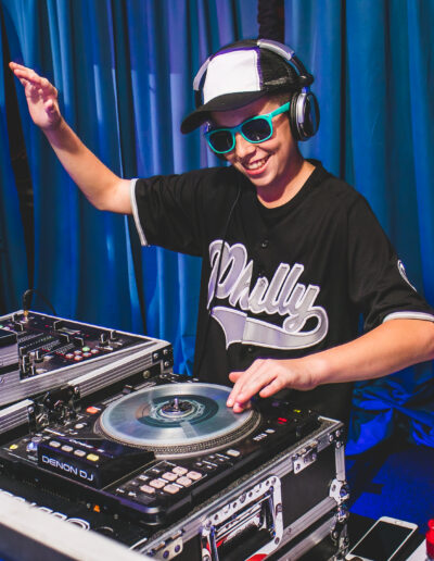 Awesome photo of the Bar Mitzvah boy wearing bright blue sunglasses and earphones as he takes over the DJ booth at Citizens Bank Park