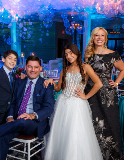 The Mitzvah family poses for a beautiful portrait dressed in coordinating themed colors of blue, turquoise and white at this ocean themed Bat Mitzvah at Vie by Cescaphe in Philadelphia