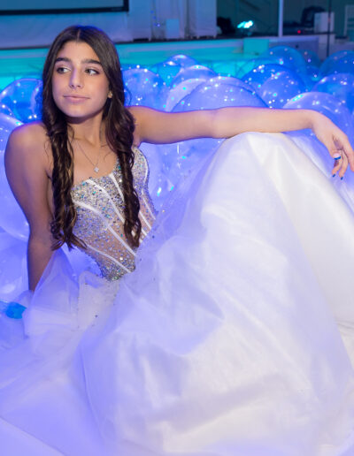 A calm relaxing look on the Bat Mitzvah girl in a white beaded gown and high top Nike's while relaxing on the dance floor amid iridescent balloons and blue lighting at vie by Cwscaphe in Philadelphia