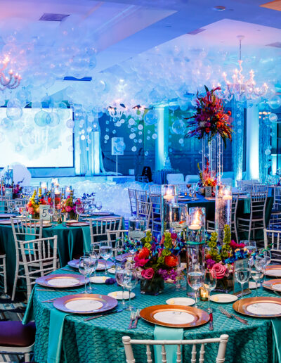 Fabulous reception room all decorated for a beautiul Bat Mitzvah illuminated with pale turquoise lighting, bubbly opal colored balloons and vibrant full centerpieces at vie by Cescaphe in Philly