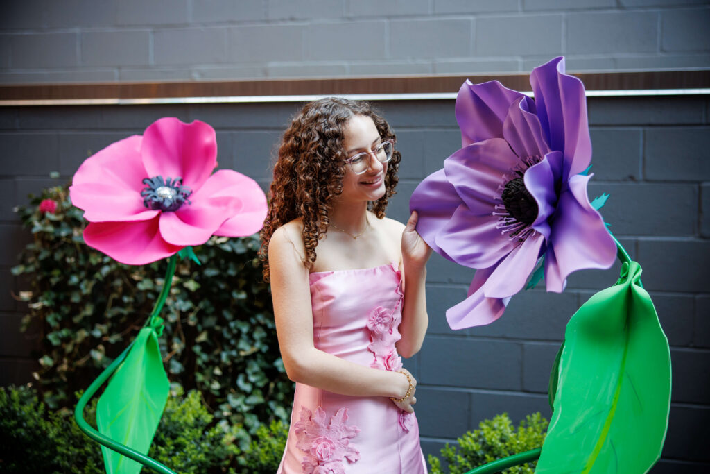 bat mitzvah girl posing with oversized colorful flower installations at Fitler Club Philadelphia courtyard